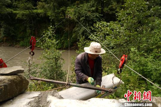 图为当地农牧民通过过江索道运输茶田所需的农用物资