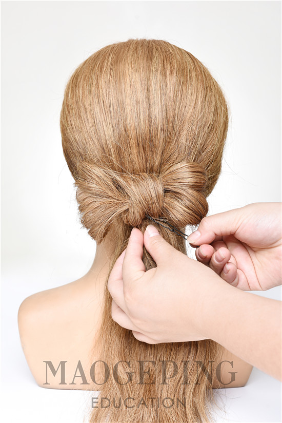 step6:将发尾的头发从蝴蝶结的中间缠绕几周后,再用发夹固定好
