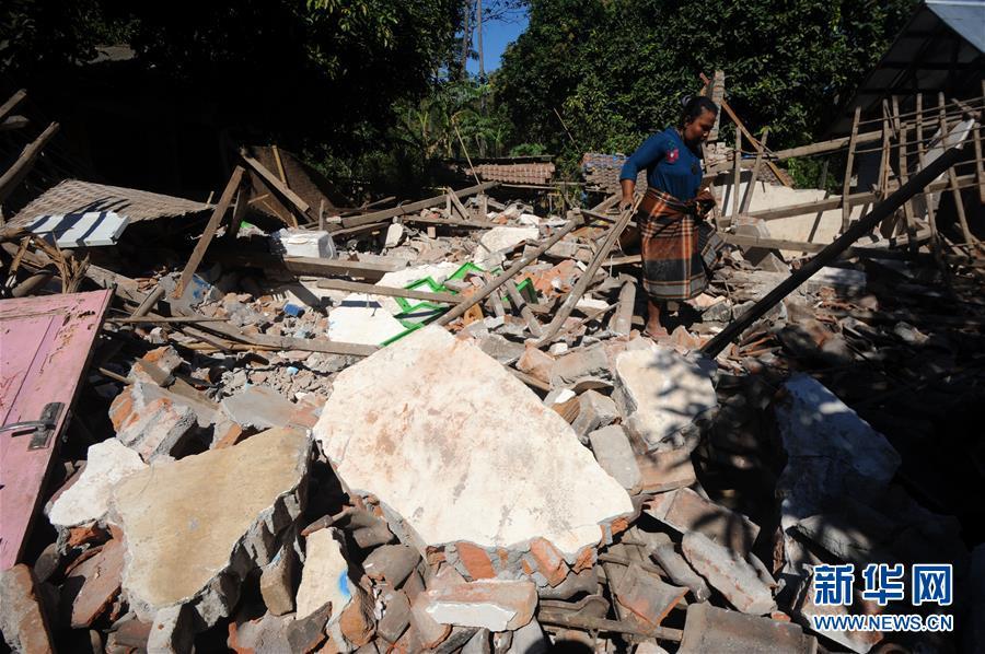 8月7日,在印度尼西亚龙目岛,一名妇女走过一处地震废墟