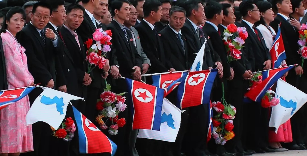 朝鲜民众手持朝鲜国旗和朝鲜半岛旗欢迎文在寅乘专机抵达朝鲜18日这次