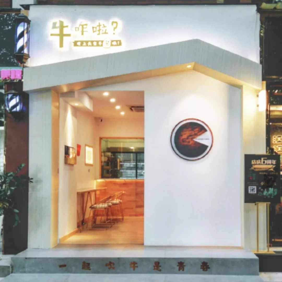 屋顶上方才是散发温馨黄光的店名在门头设计了倾斜凸出的屋顶店铺的