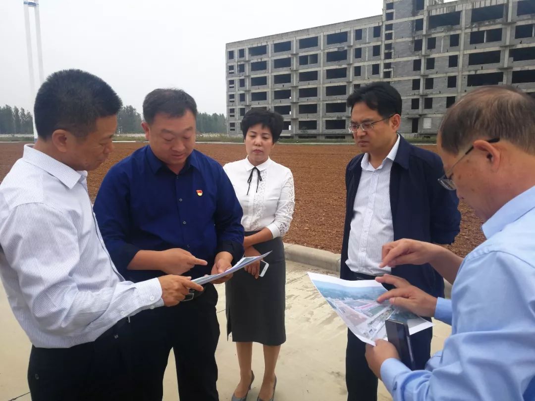 二)向伊川县县委李新红书记(左二)汇报新大牧业伊川扶贫项目建设进展