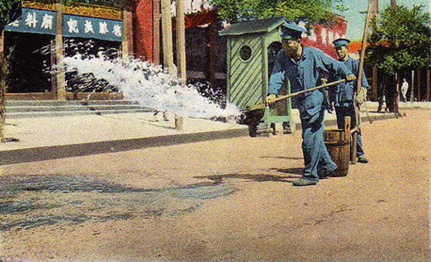 照片拍摄于民国时期,北京的路政工人在街道上洒水
