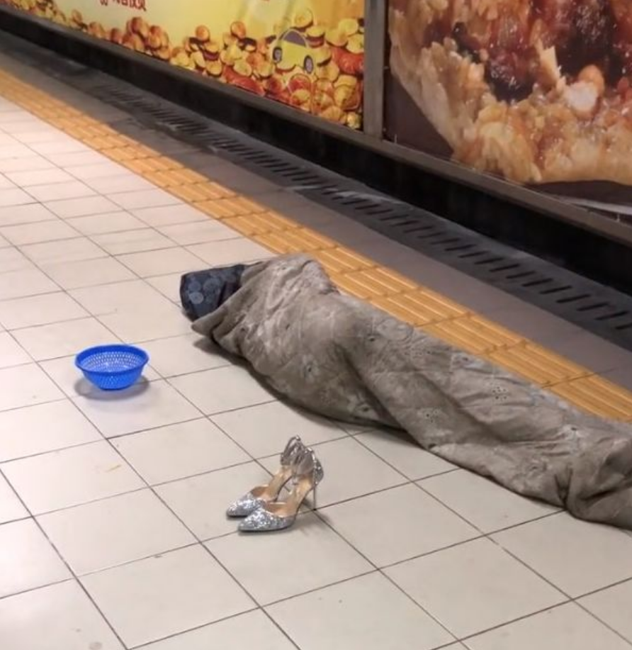 乞丐在地铁站裹着脏被子睡觉乞讨一双豪华高跟鞋成了亮点