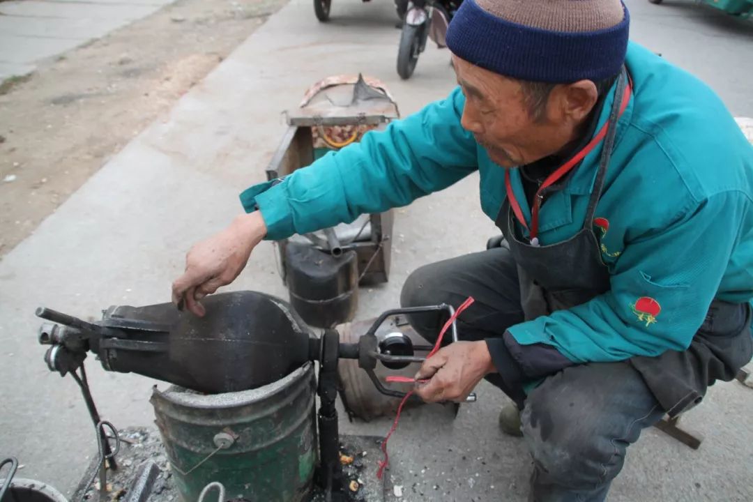 顺着方向看去,一位大爷正在操作着老式手摇爆米花机,动作不紧不慢,有