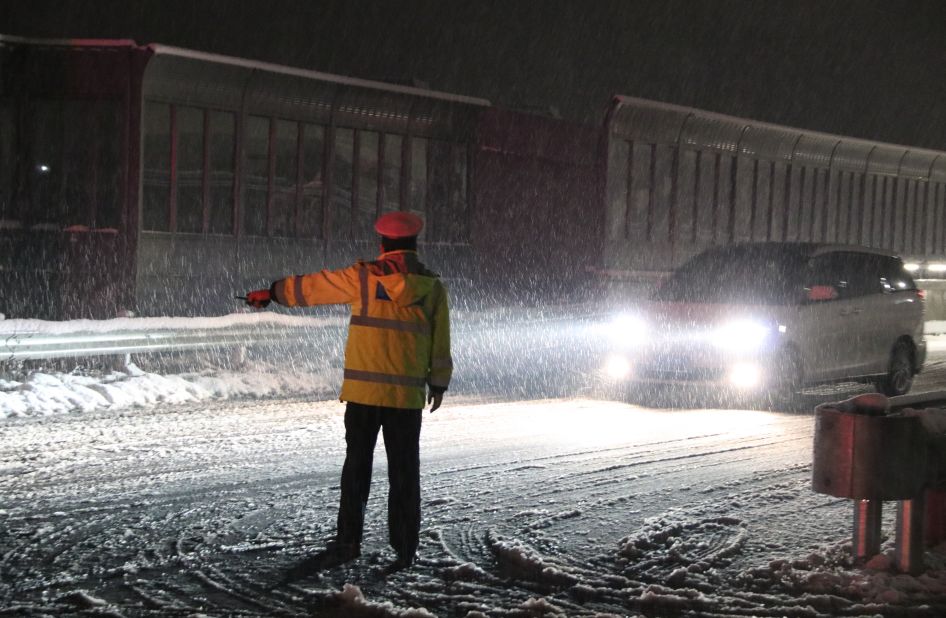 民警張葉帆站冒雪指揮疏導車輛