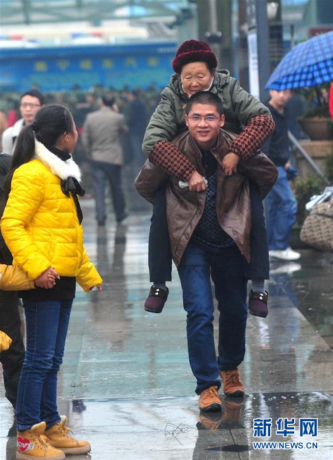 2013年1月26日,在广西南宁火车站广场,蒋先生背着岳母在雨中行进