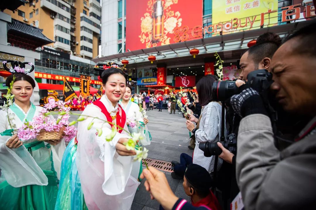 和市民亲切打招呼演员们身着汉服在花市路段进行巡游表演今年的开市