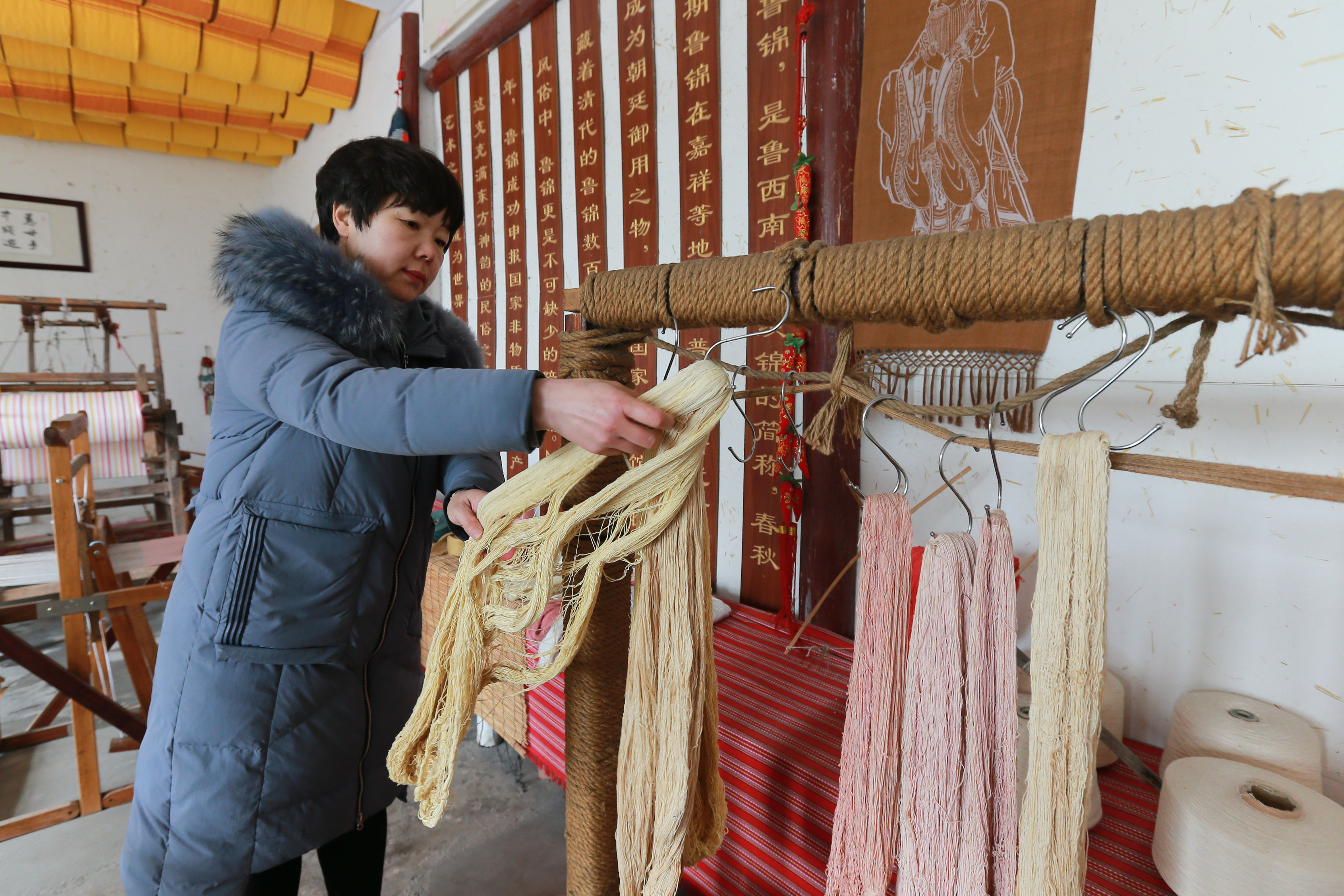 2月15日,在山东省济宁市嘉祥县一家鲁锦纺织企业,工人在整理晒干的