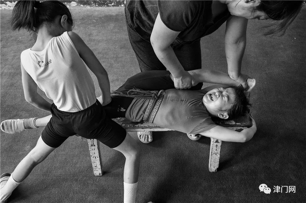 老师在帮一名9岁学生做压腿动作老师在帮助八岁的女孩做腰的训练短暂