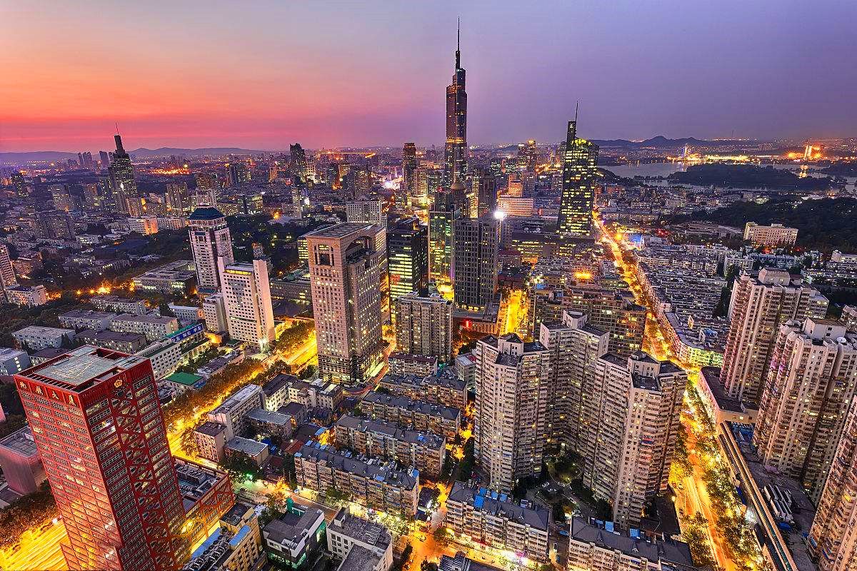 这是一张城市天际线的照片，展示了高楼大厦、璀璨的灯光和黄昏时分的天空。