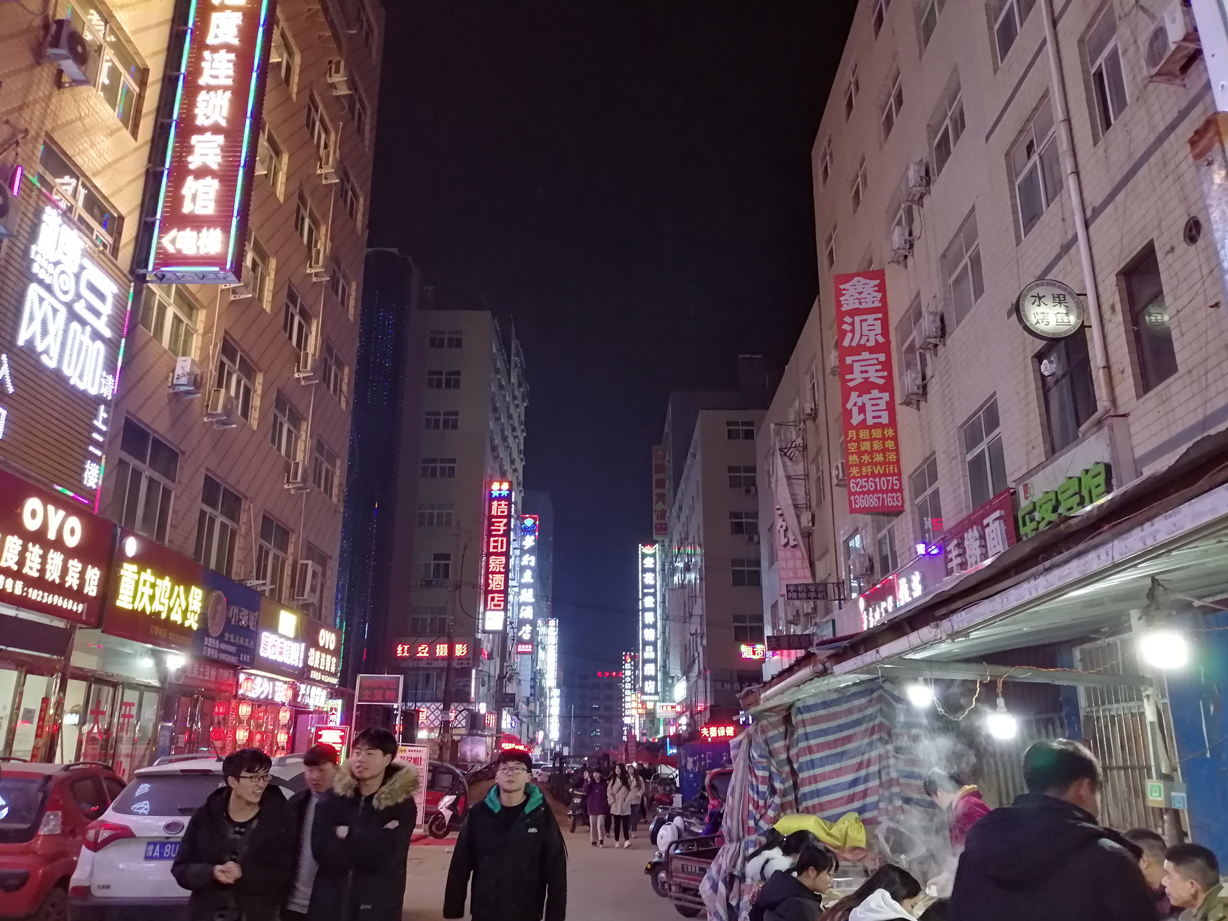 郑州夜晚的城中村,霓虹灯闪烁,宾馆一家挨着一家