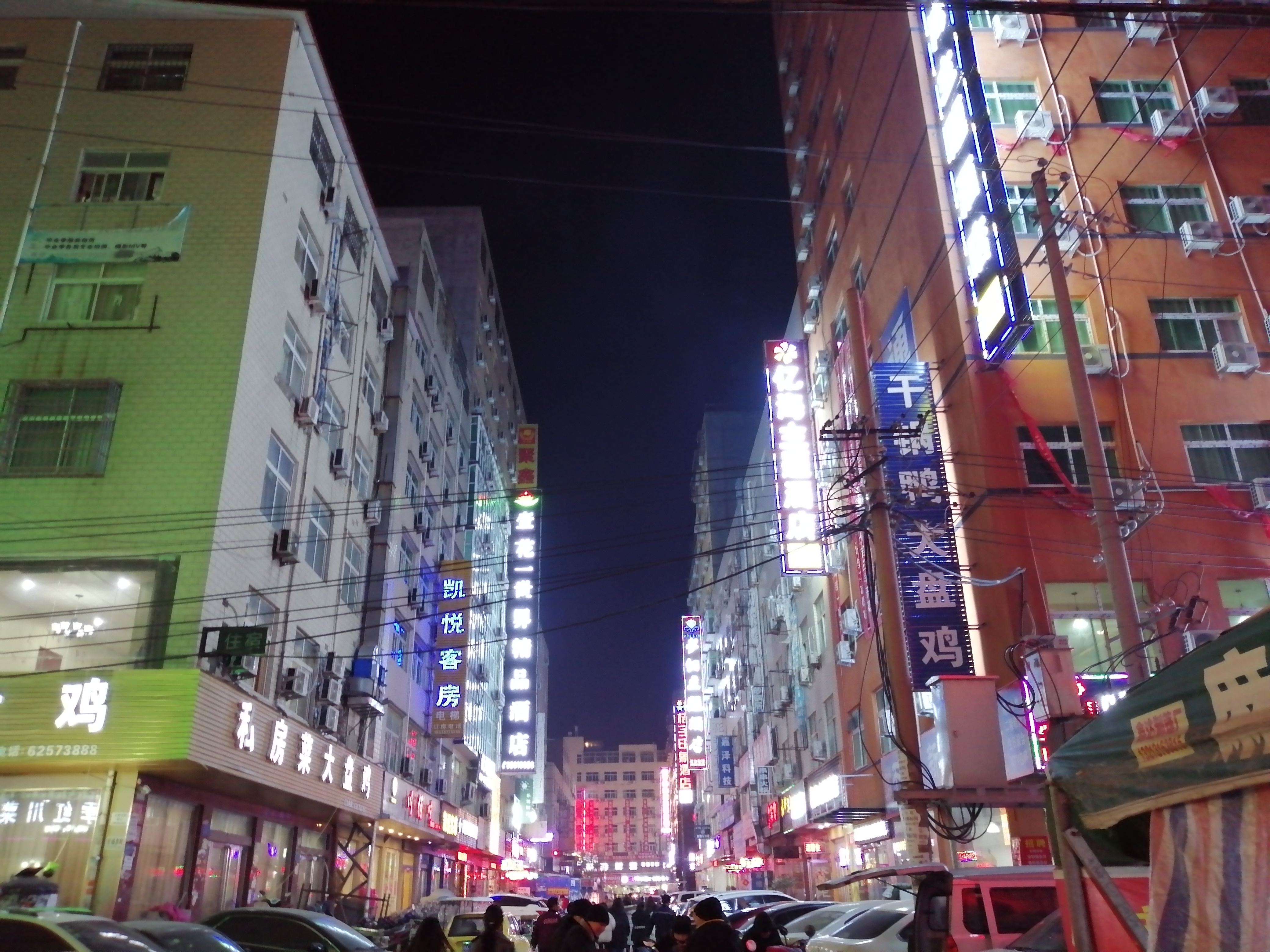 郑州夜晚的城中村,霓虹灯闪烁,宾馆一家挨着一家