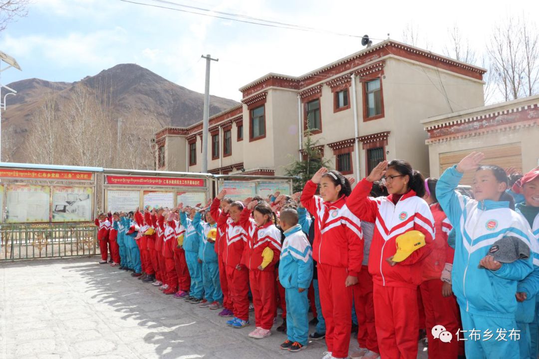 当仁布乡小学国旗护卫队的学生护卫着神圣的国旗出现时,在场所有人