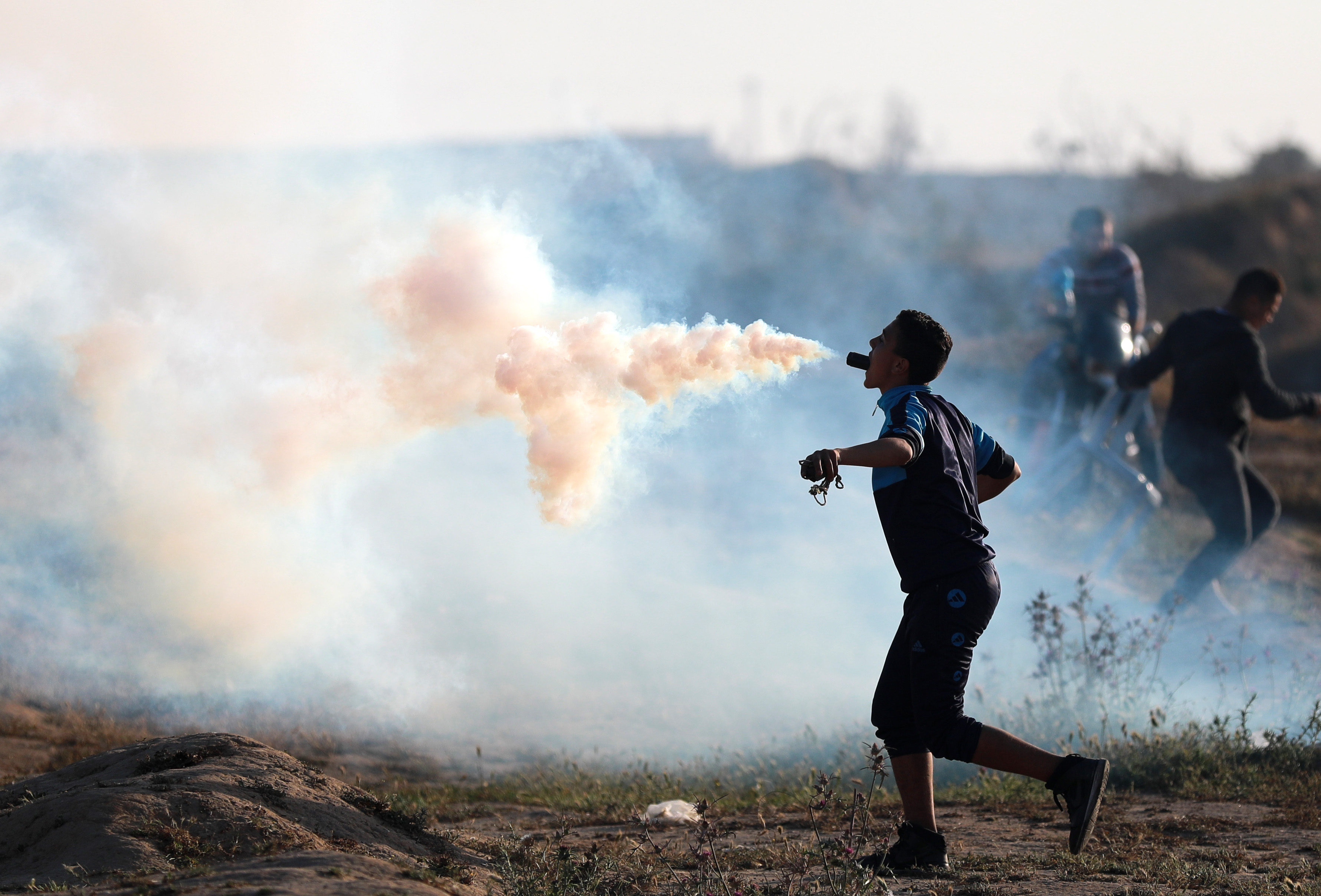 赖杰难民营以东,一名巴勒斯坦示威者用嘴叼起以色列士兵发射的催泪弹