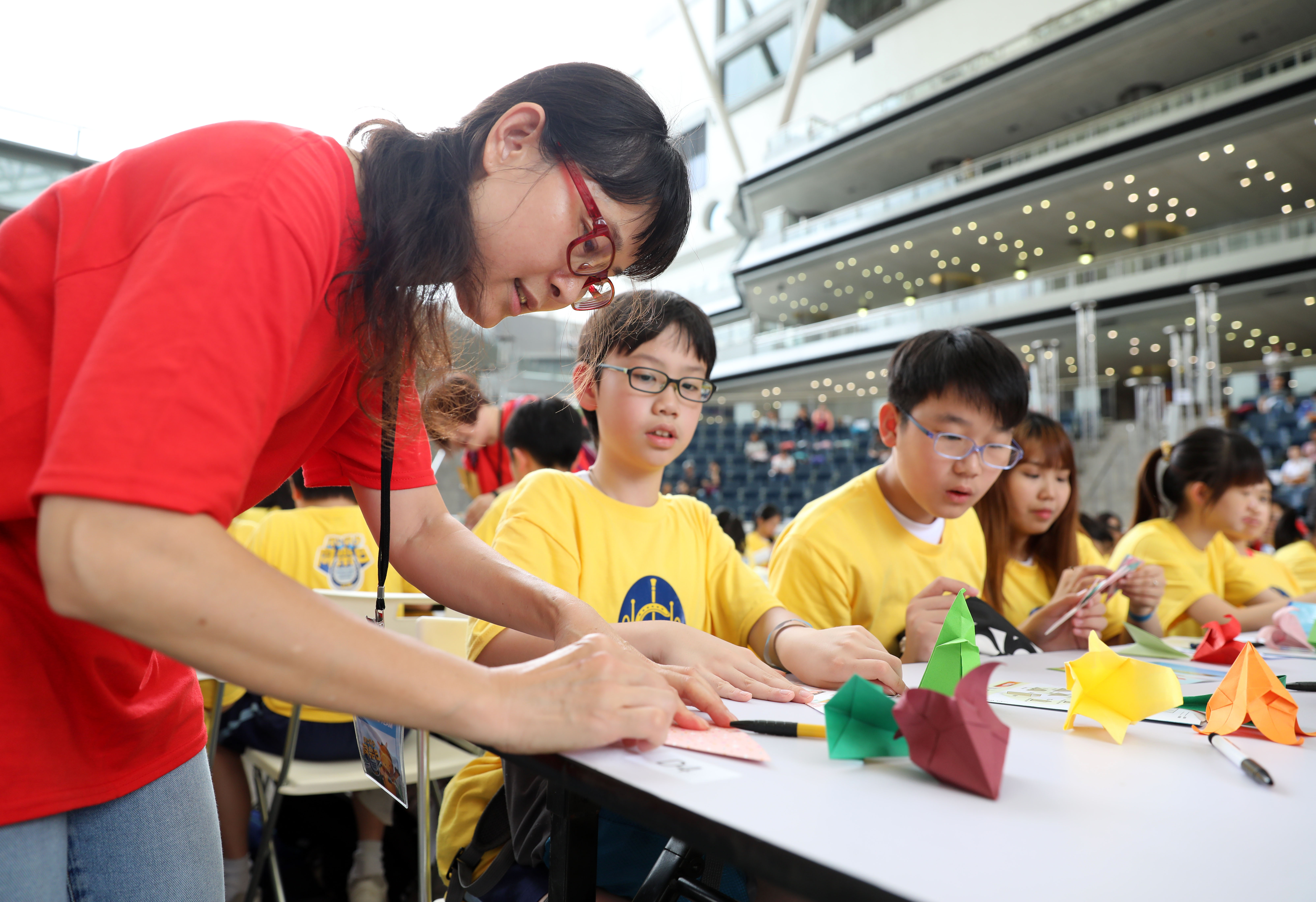 4月19日,工作人员在活动现场指导学生折纸.