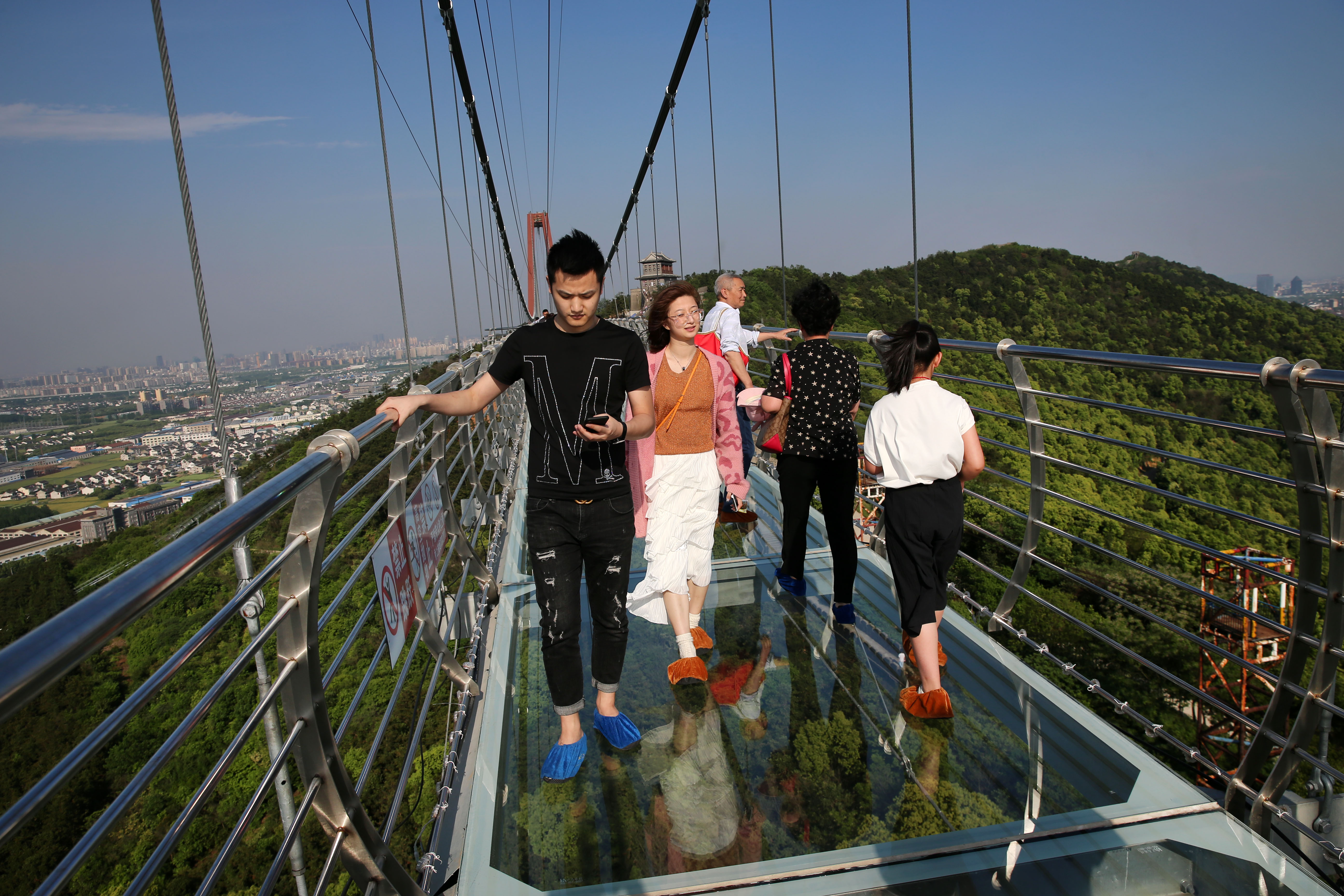 5月4日,游客在江苏省江阴市华西世界探险公园内的凌空玻璃桥上游.