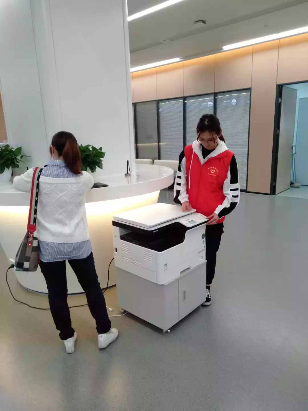 电大志愿者们穿着红马甲在萧山区行政服务中心3楼大厅助力教师资格