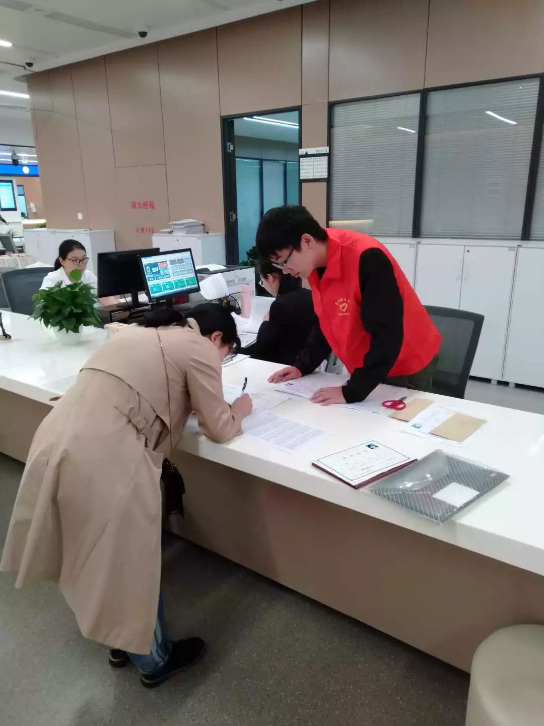 电大志愿者们穿着红马甲在萧山区行政服务中心3楼大厅助力教师资格