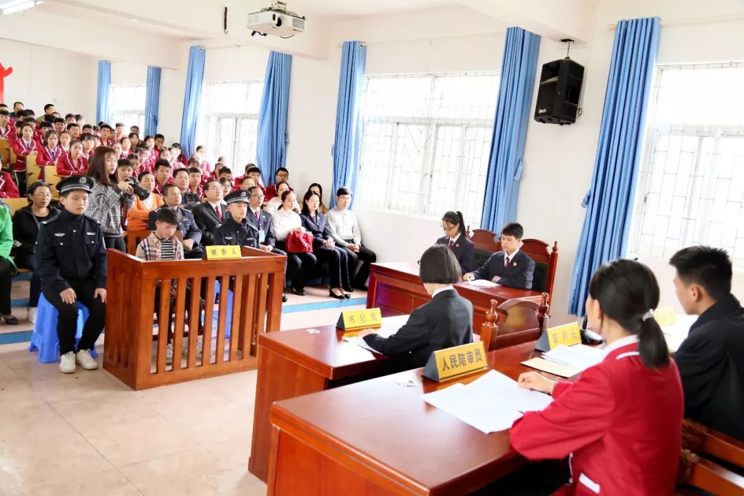 "公诉人" 和"法官"肃然危坐,老师和同学们聚精会神地观看案件"公审"