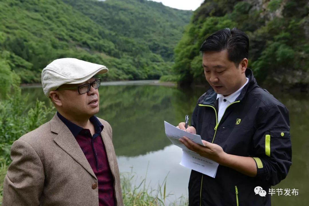毕节市广播电视台总编辑叶光良(左)在落脚河畔与记者商量主持词