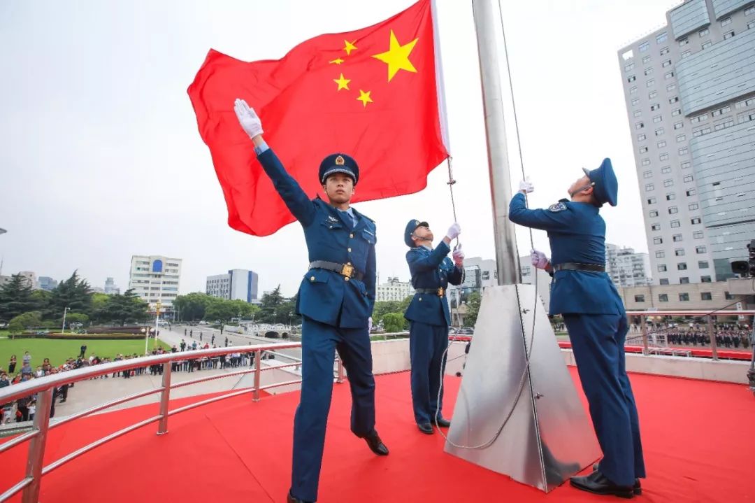 迎风飞扬鲜艳的五星红旗舒展在天空中升旗手右臂猛地一扬出旗,系旗