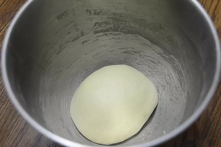 2,揉至面团光滑面筋扩展时加入软化黄油,继续揉至能拉出薄且有韧性膜