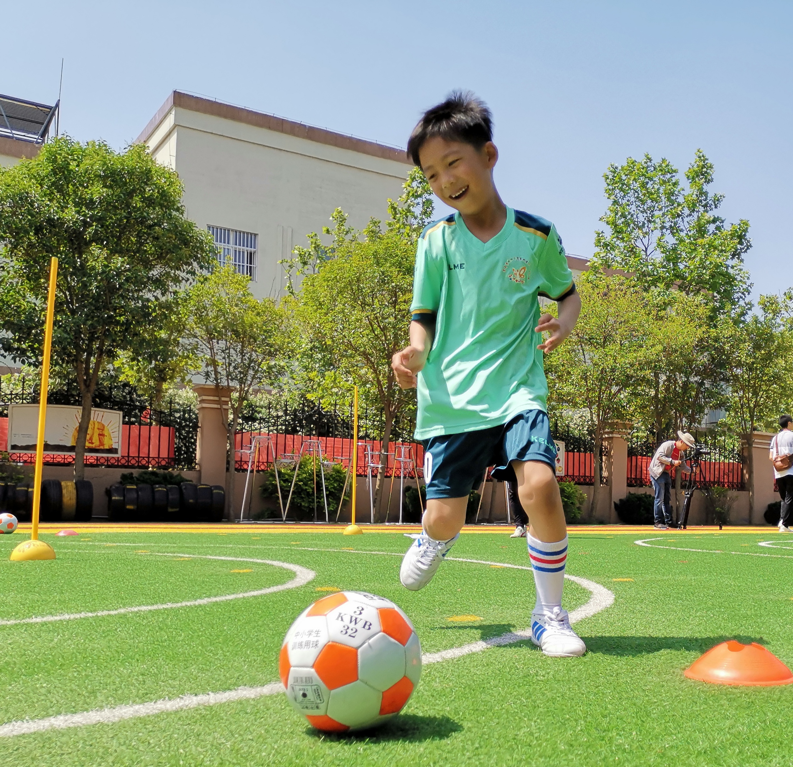 5月16日,青島市城陽區順德居幼兒園的小朋友們在教練指導下練習足球.