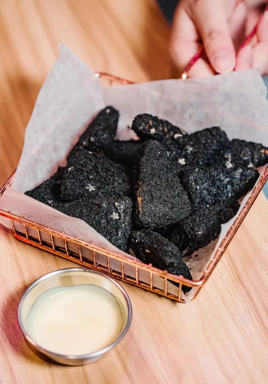 别被外表给骗了,这不是木炭,而是裹了一层墨鱼汁的炸鸡块,蘸上酱料