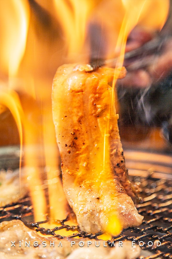 炭火上炙烤的五花肉,滋滋冒油,过多的脂肪燃成一簇火,火焰中,肥瘦完美