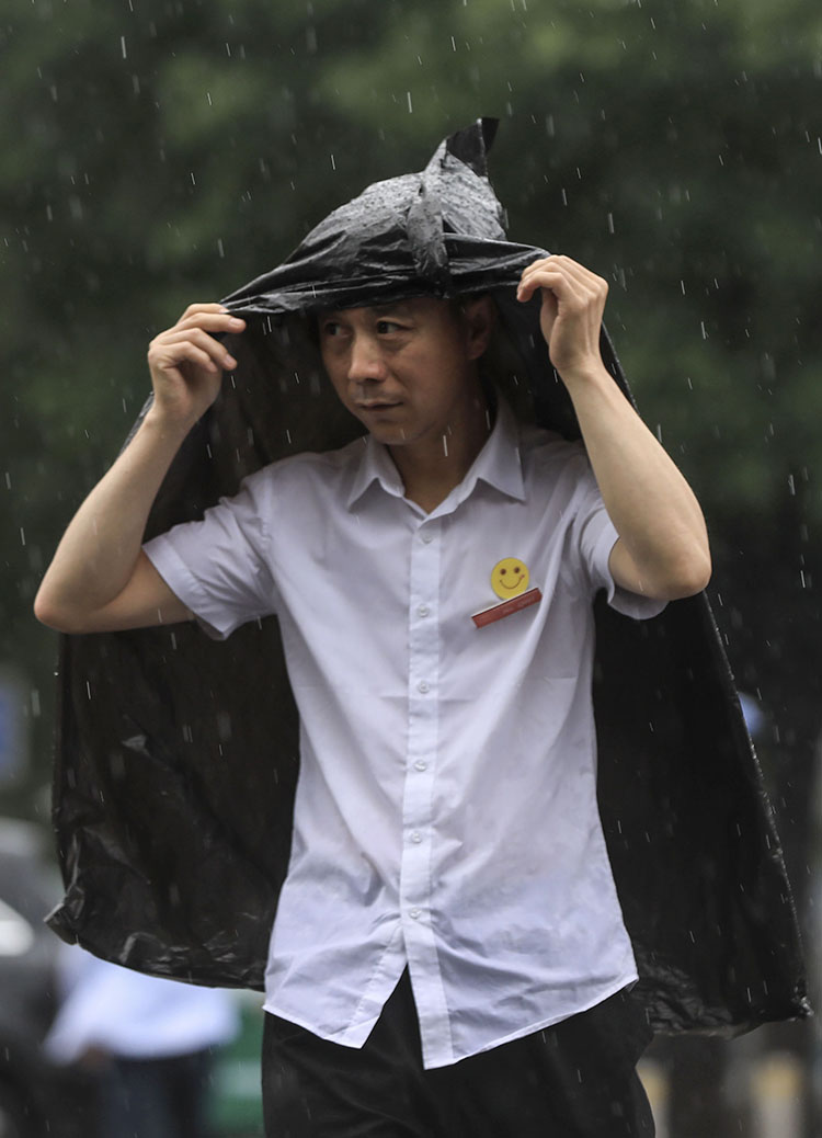 知春路,一位市民用衣服遮雨.