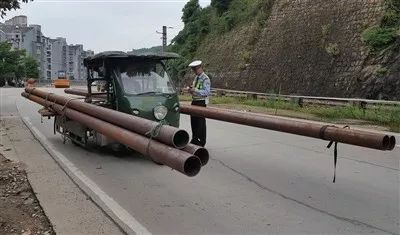 近日,一辆违规超长运输铁管的三轮摩托车被执勤的交警拦下.