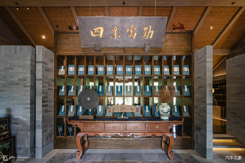 圆形的接待台后是规整摆放在书架上的竹简笔筒,方形的景观池如一樽上