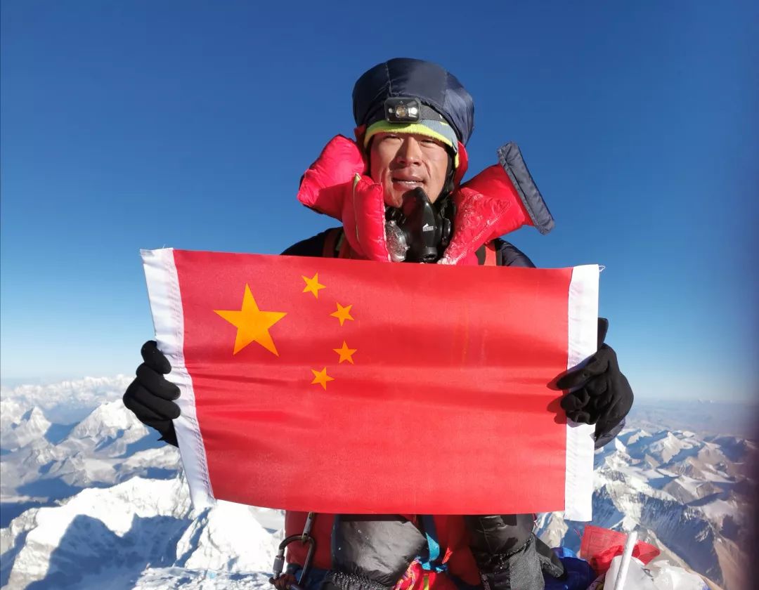 何玉龙登顶珠峰后,举着国旗留影.受访者供图