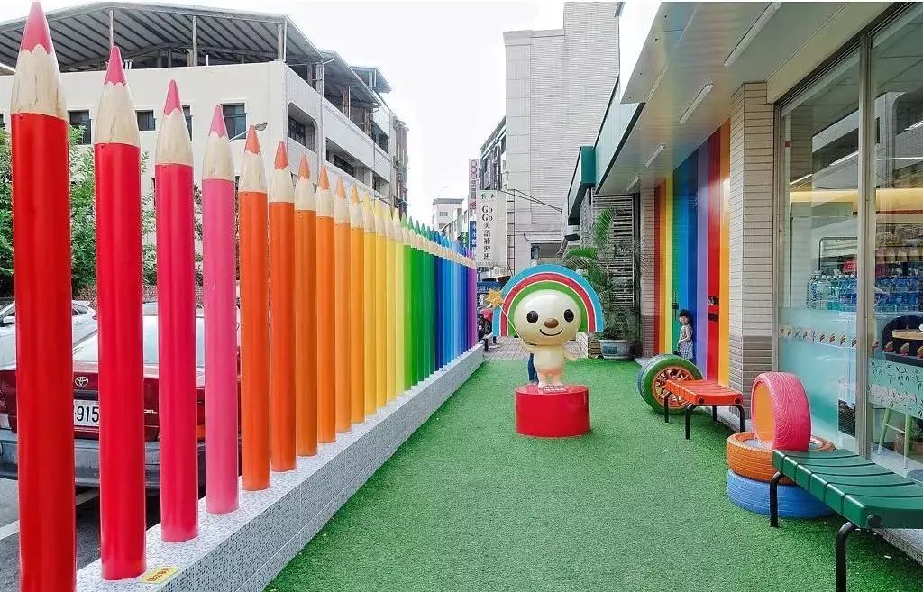 以富有童趣的彩色铅笔取代生硬的围墙,后方的墙面上则是缤纷的彩虹墙