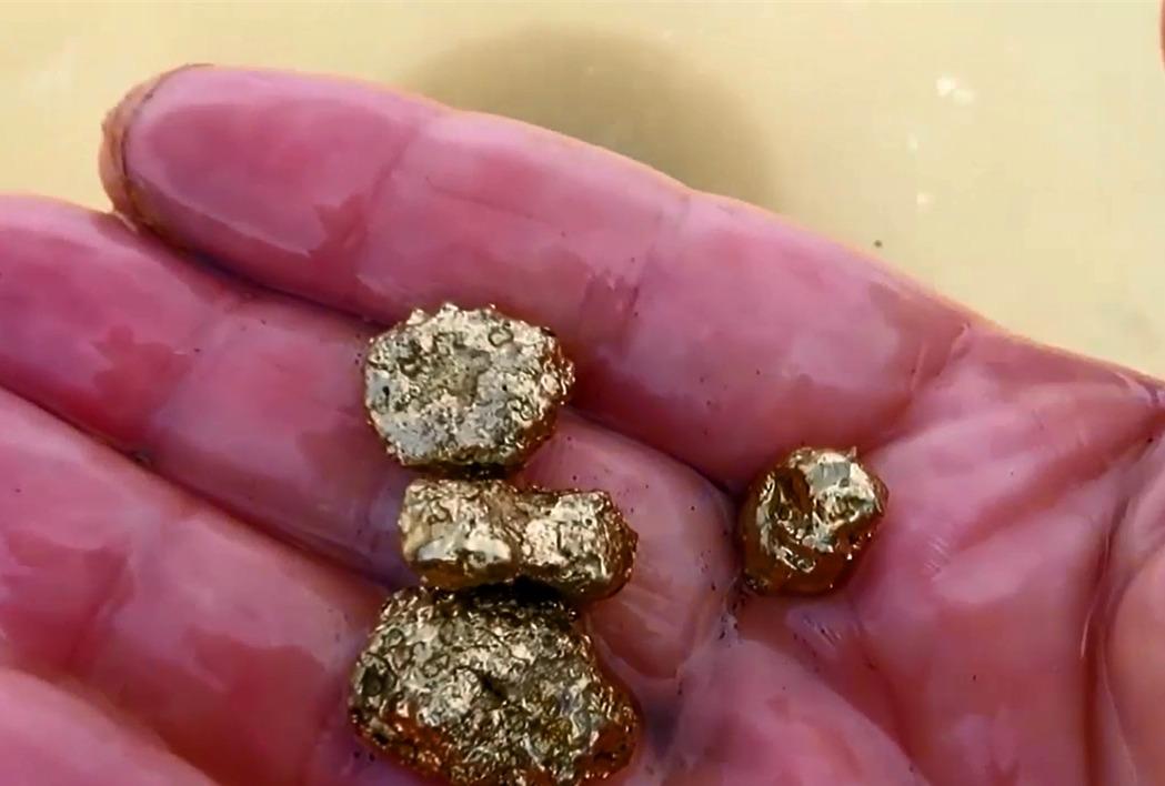 男子用磁铁在水边吸宝,往河沙里一放,还真有意外收获