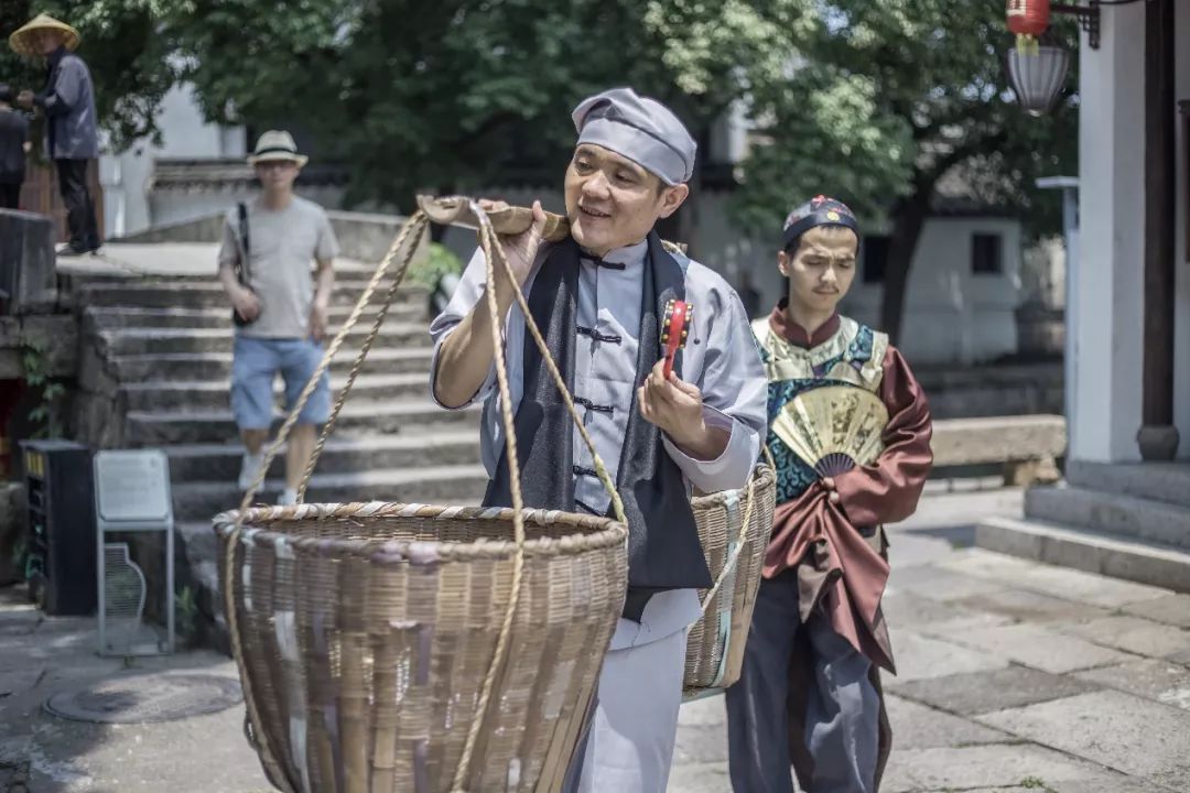 穿梭在青石板桥上的卖货郎满脸洋溢着幸福的微笑他的箩筐里装着满满的
