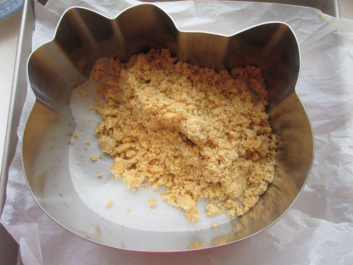 擀面杖压碎成渣,我这个是用料理机打碎的,把黄油融化,倒入饼干渣拌匀