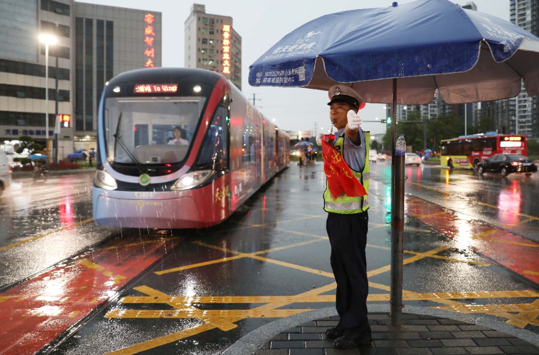 6月11日晚,龙华现代有轨电车沿线的交通协管员在路口指挥交通环卫工