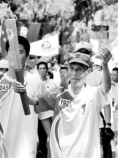 图为2008年北京奥运会,江西瑞金站第192棒火炬手王汝申手举奥运圣火.