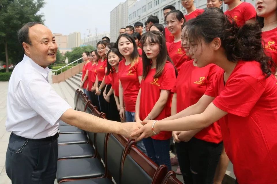 渭南师范学院党委书记卓宇,校长赵曼与各位志愿者在厚德楼前握手并