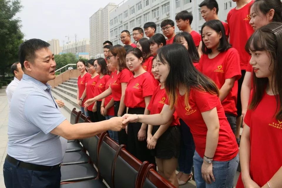 校长赵曼与各位志愿者在厚德楼前握手并拍照