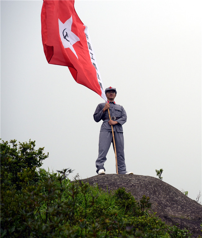 在建党日当天,老党员带着自己的儿子,身穿红军军装,举着工农红军旗帜
