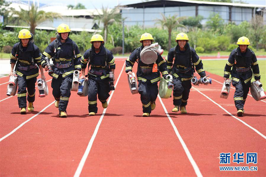 7月1日,消防队员在训练中携带灭火器材冲刺新华社发(周杨东 摄)