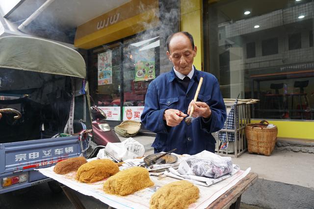 生意,83岁的吴大爷不急不躁,慢悠悠拿起烟竿,挖一撮黄烟丝压在烟筒里