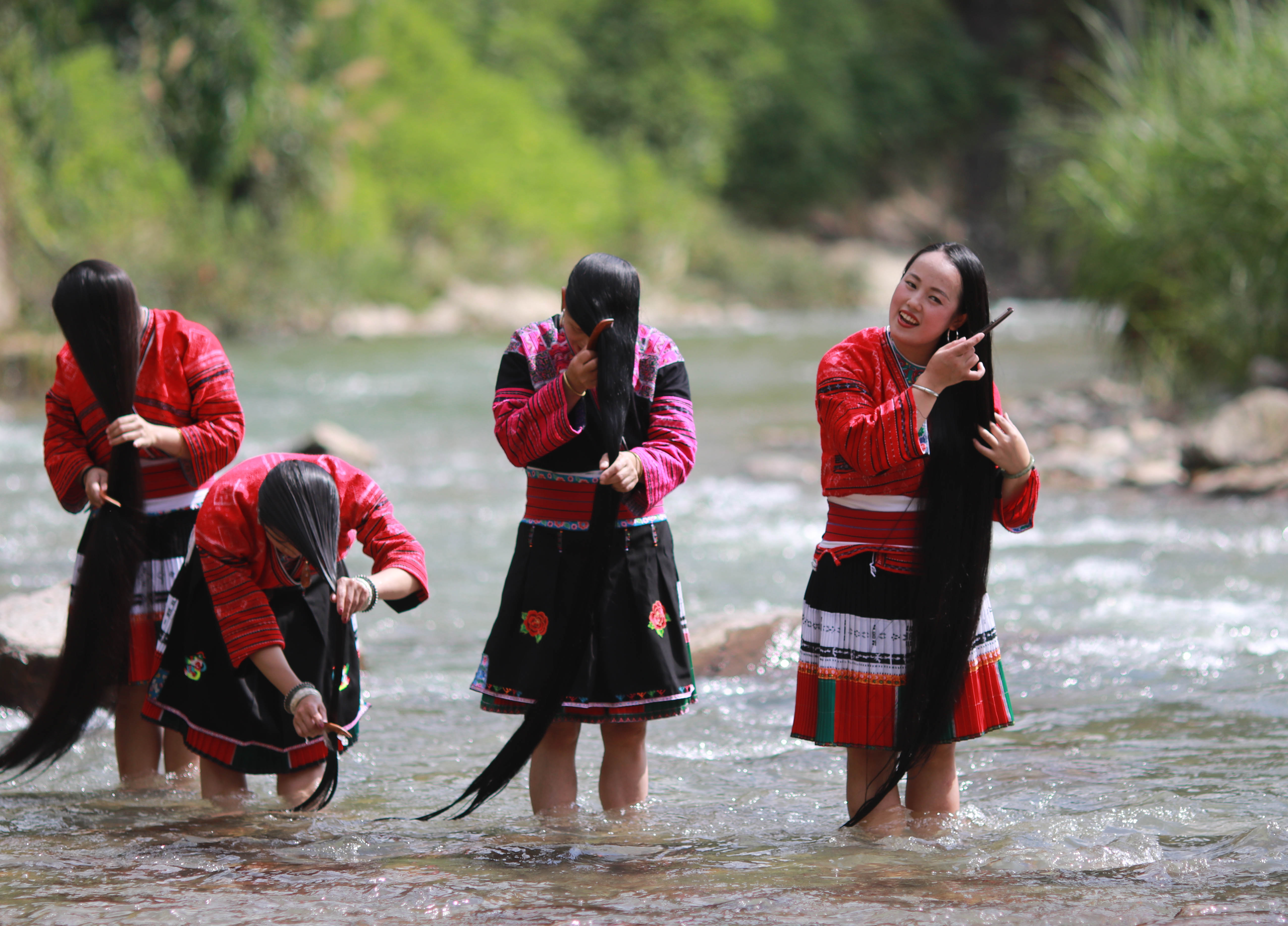 7月4日,在广西龙胜各族自治县龙脊镇黄洛瑶寨,红瑶妇女在河中洗长发