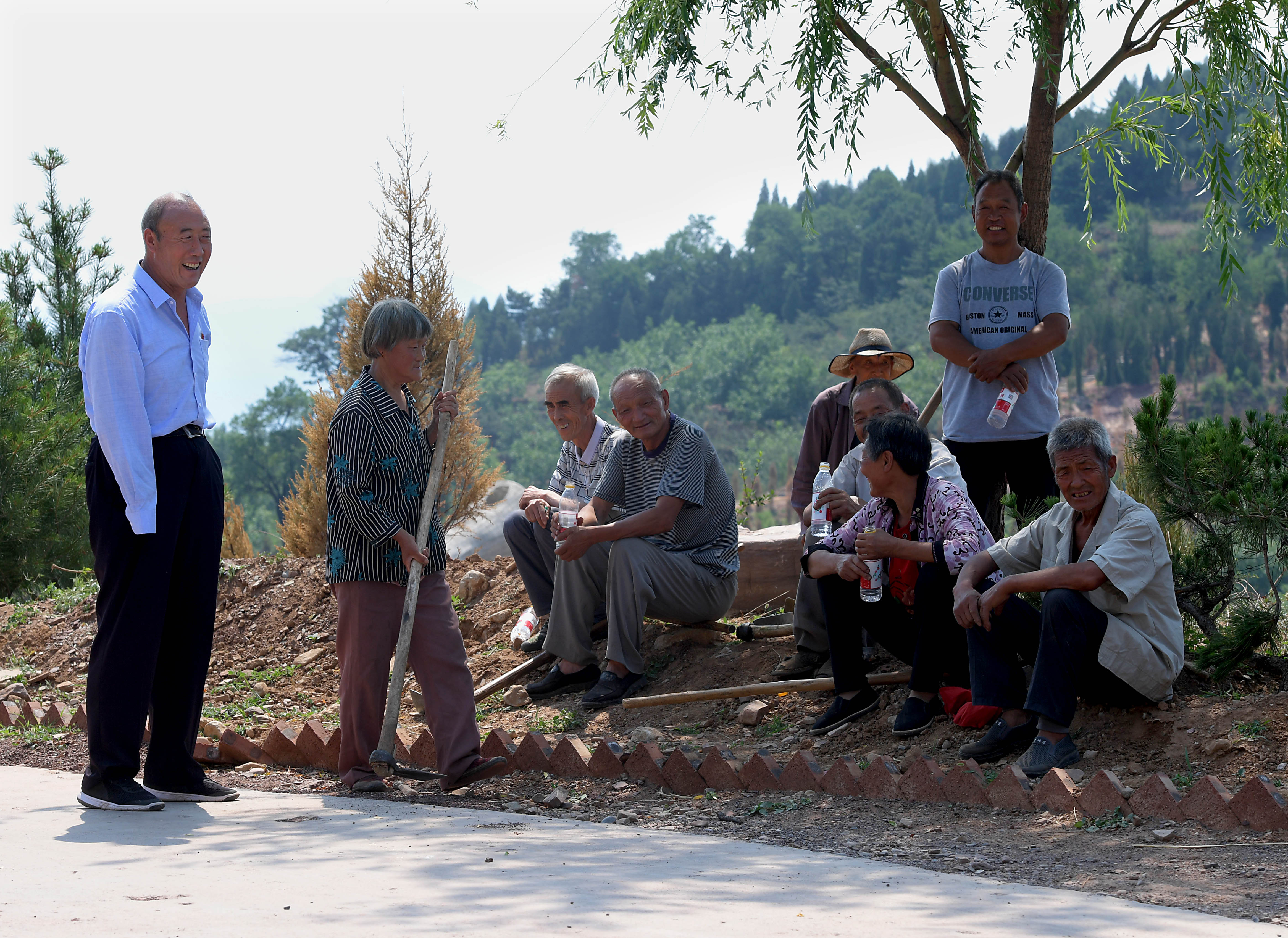 7月3日,在林州市任村镇盘龙山村,王生有(左一)和村民在劳动间隙聊天.