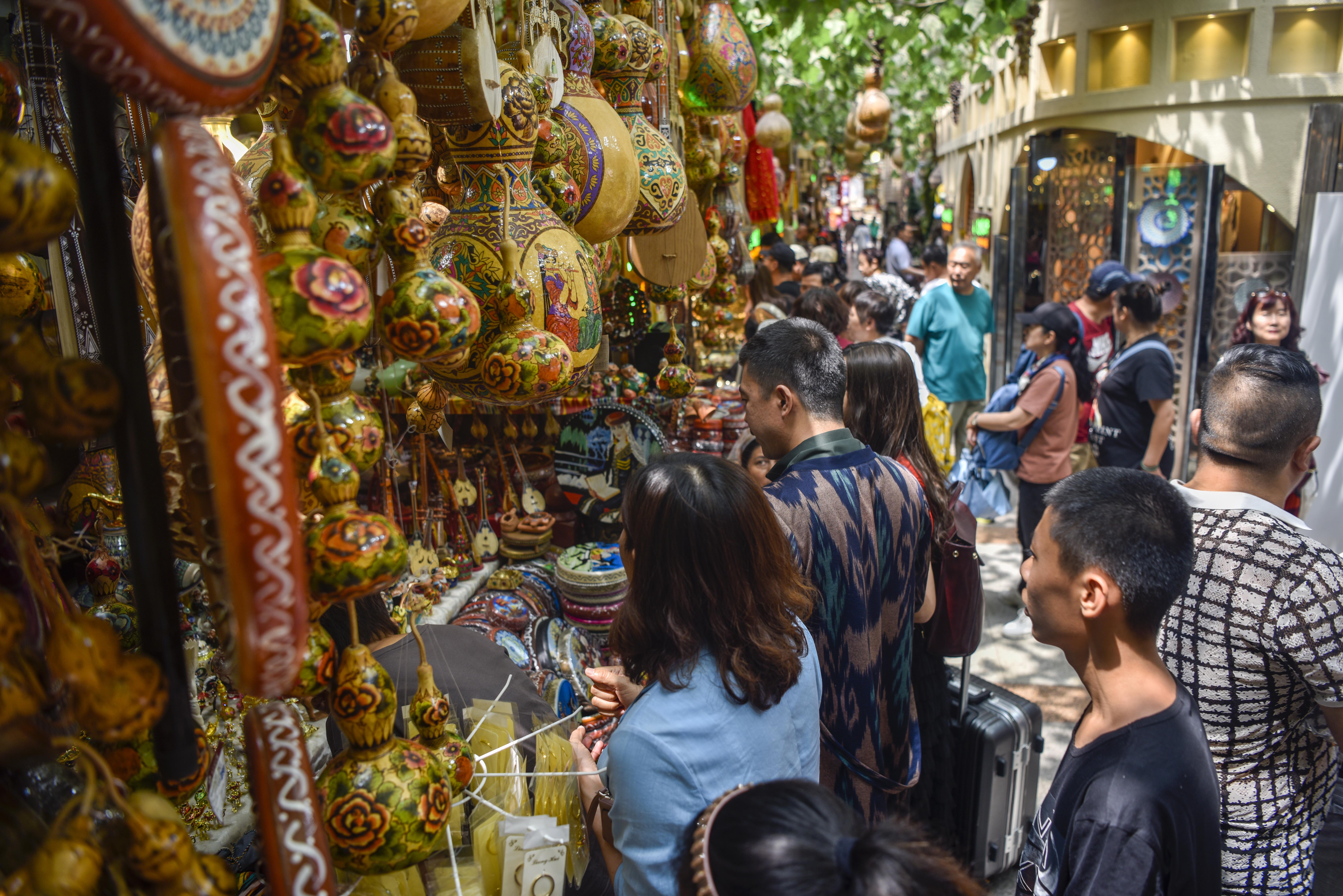 游客在乌鲁木齐国际大巴扎挑选工艺品(7月5日摄 新华社记者 赵戈 摄