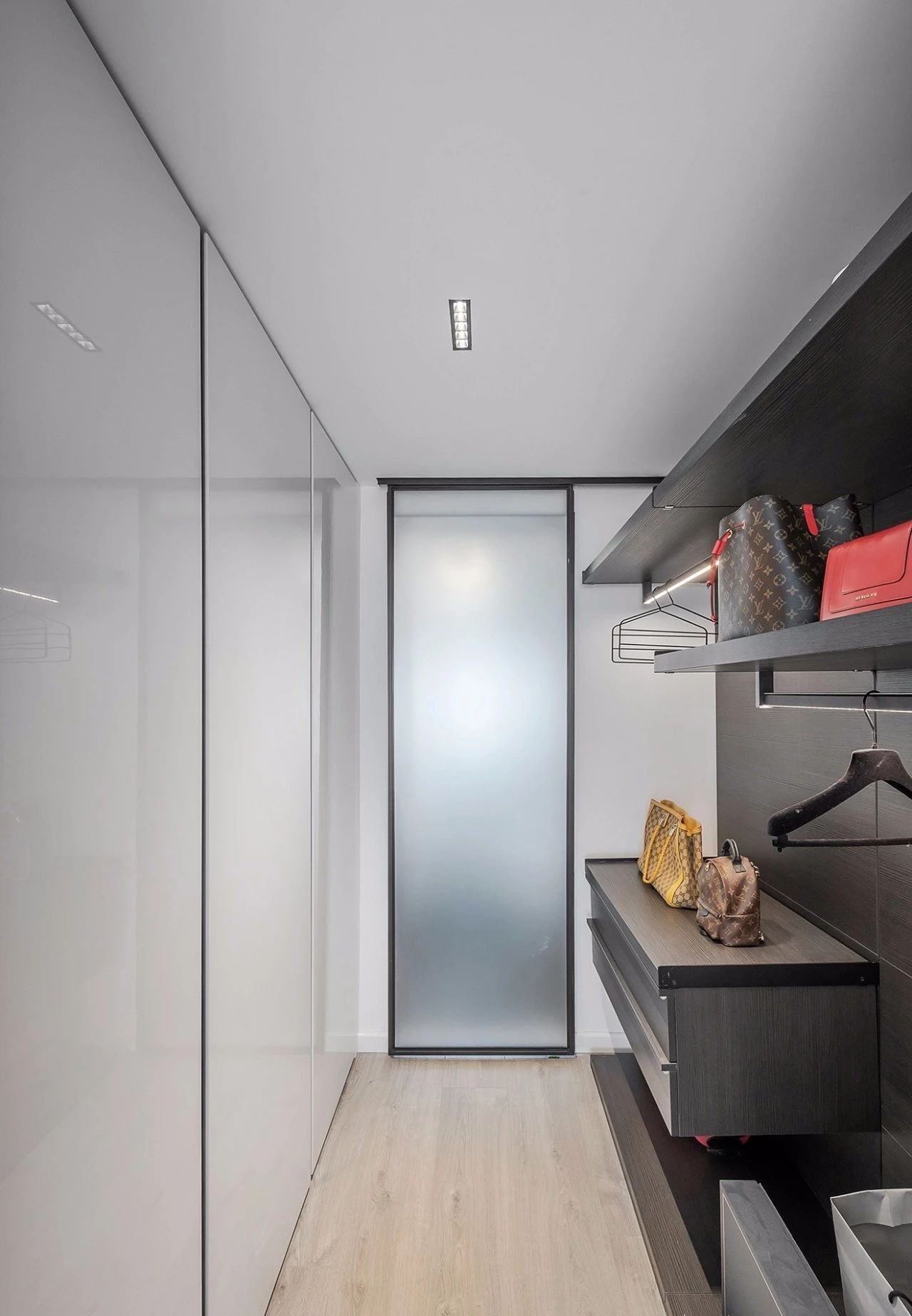 衣帽间用磨砂玻璃移门隔开,内部设置主动感应灯,两边不同的柜体