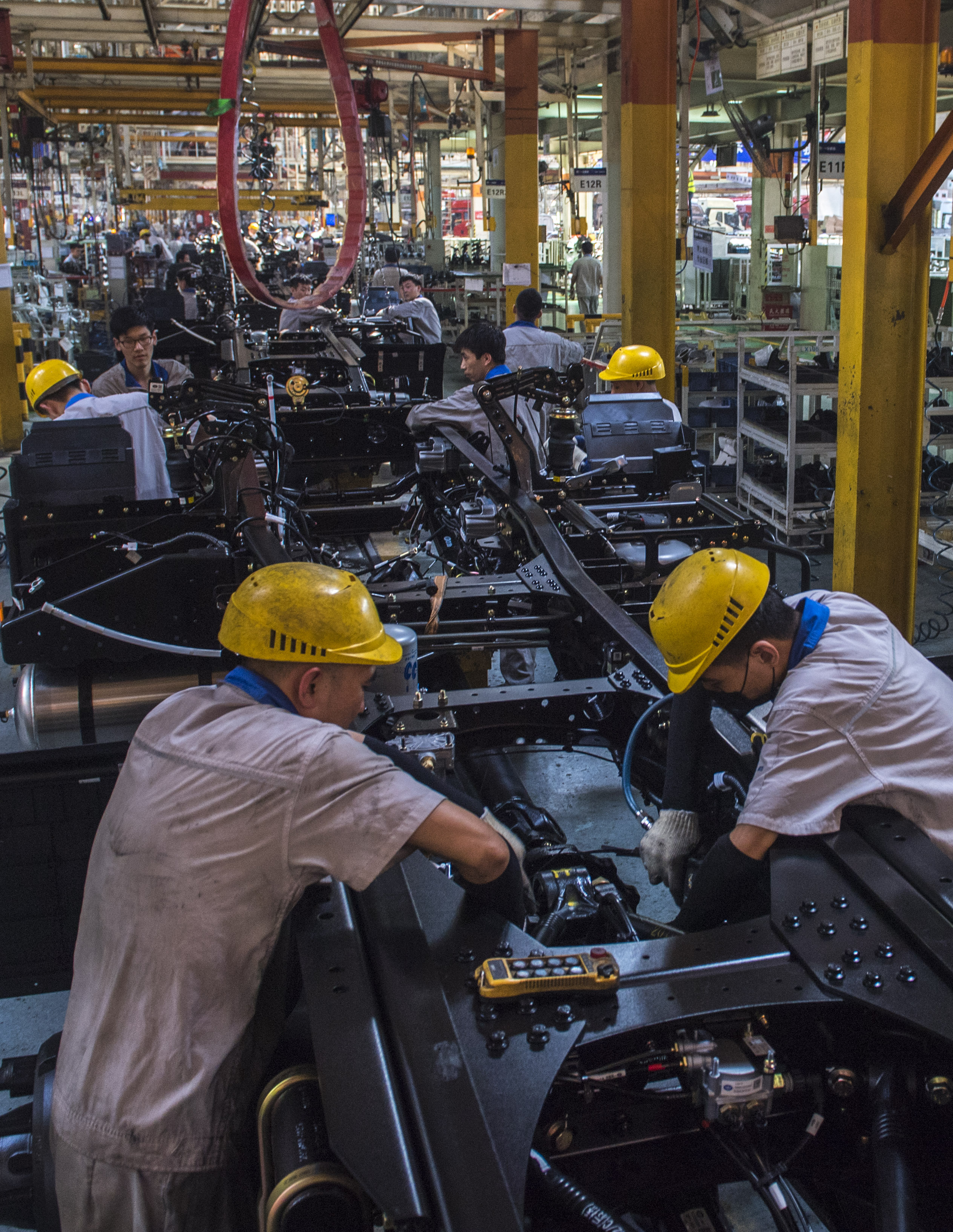 一汽解放職工在位於吉林長春的總裝車間內進行車輛裝配作業(6月12日攝